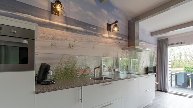 A modern kitchen with a large island, stainless steel appliances, and a view of the outdoors. - Holiday Home on Car-free Park Garnekuul (Callantsoog)