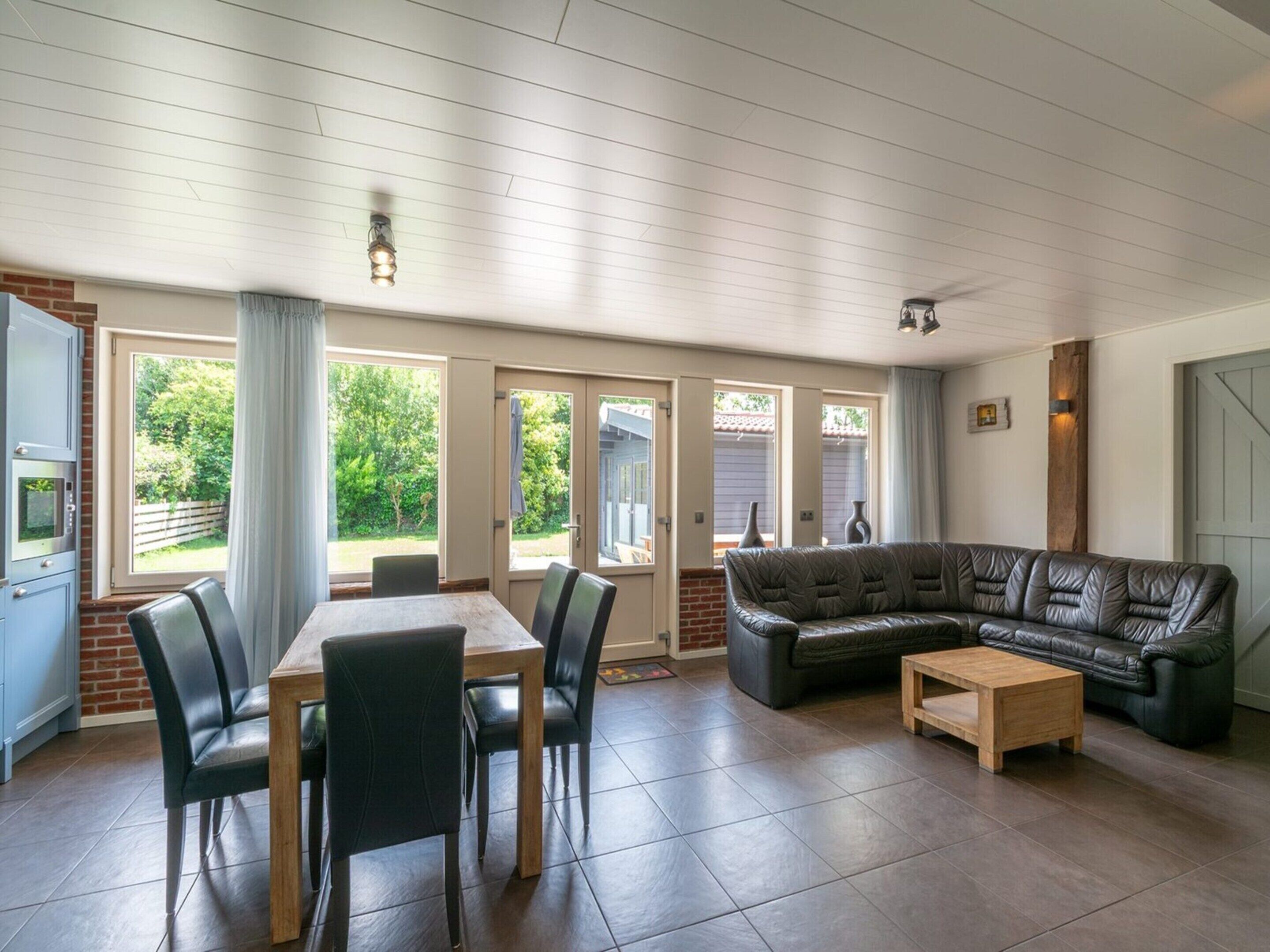 A spacious living area with a dining table, chairs, a leather sofa, and a coffee table.