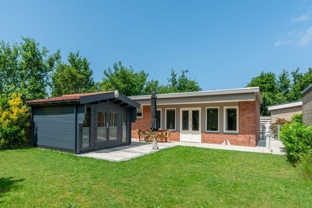 A modern house with a garage, a patio with outdoor furniture, and a well-maintained lawn.