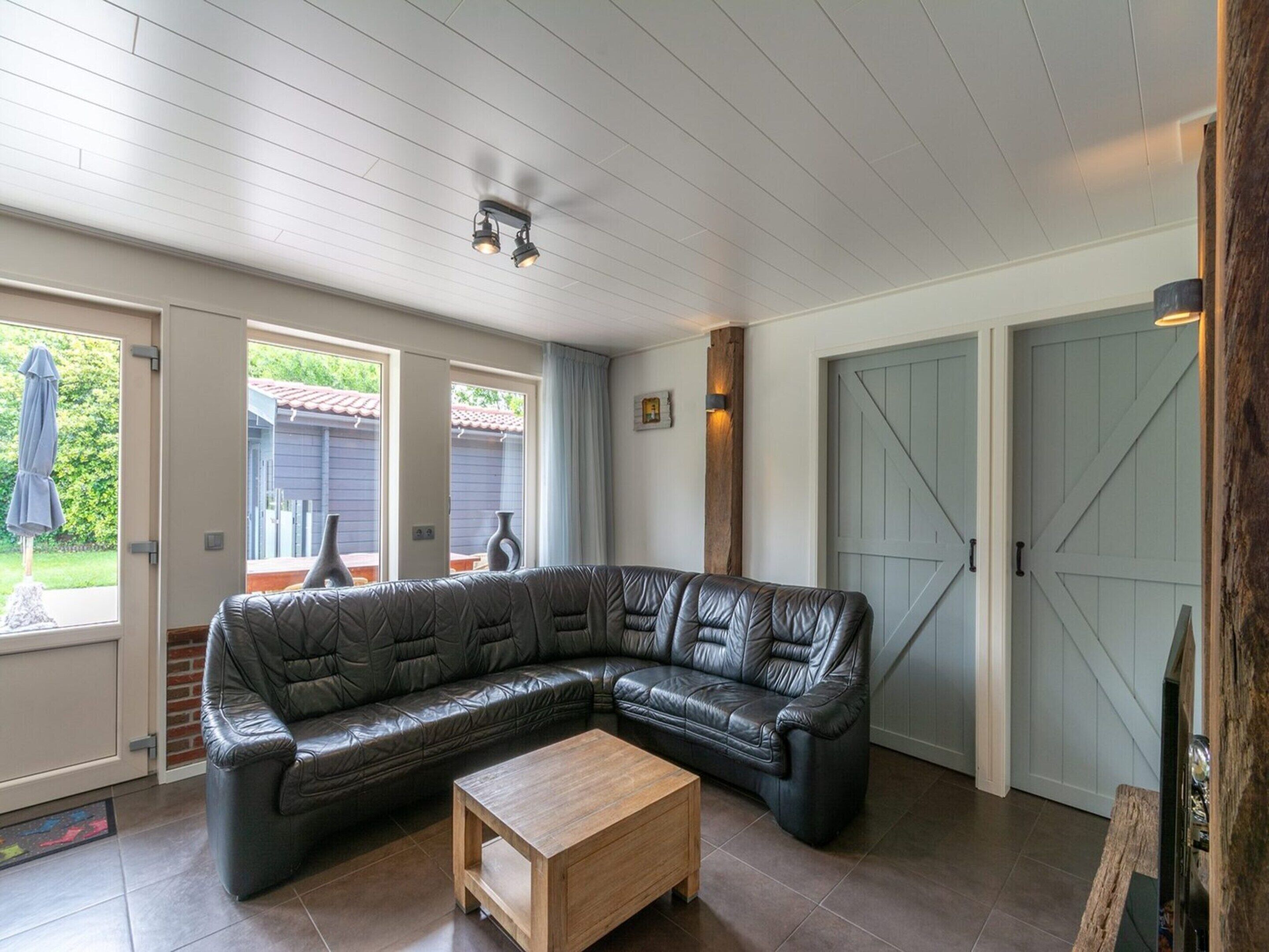 Un salon moderne avec un canapé d’angle en cuir, une table basse en bois et une grande porte coulissante.