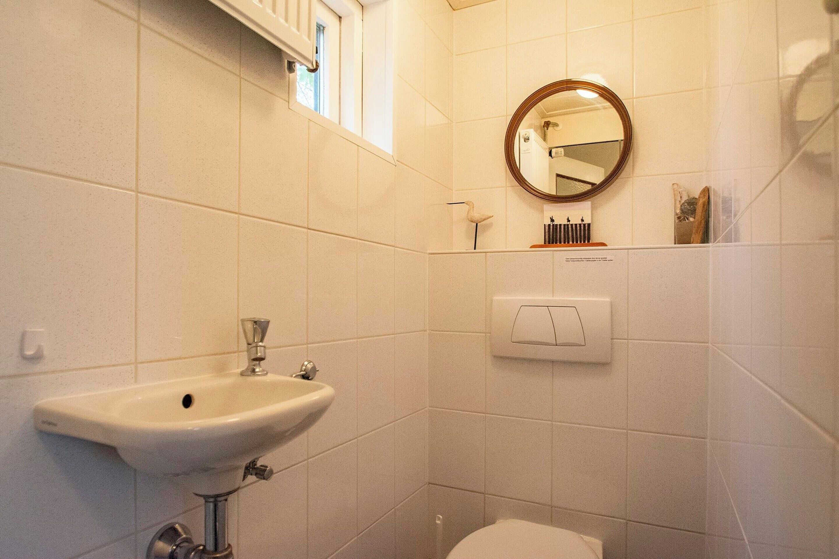 Ein Badezimmer mit einem weißen Waschbecken, einer Toilette, einem Spiegel und einem Handtuchhalter.