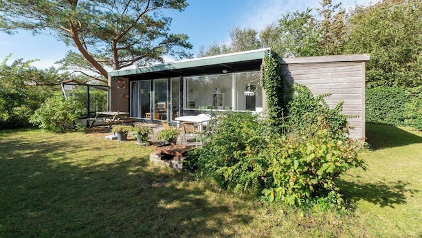 A modern house with a glass extension, a patio with outdoor furniture, and a well-maintained garden. - Child-friendly Garnekuul 81 Bungalow (Callantsoog)
