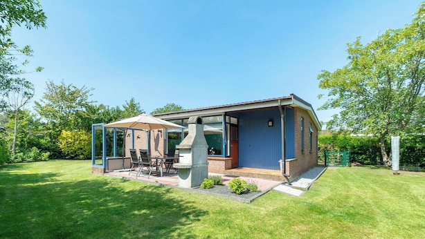 Une maison moderne dotée d’un patio, d’un barbecue et d’un espace salon abrité.