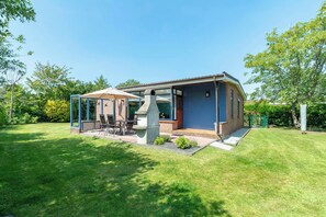 A modern house with a patio, a barbecue grill, and a covered seating area. - Eureka 78 Bungalow With Enclosed Garden (Sint Maartensvlotbrug)