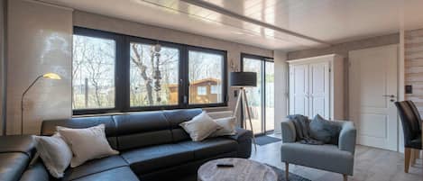 A modern living room with a sectional sofa, a round coffee table, and a grey armchair.