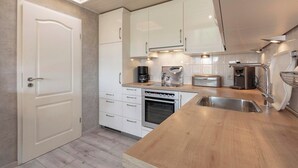 A modern kitchen with white cabinets, a wooden countertop, a built-in oven, and a skylight. - Bungalow at Garnekuul Park With Garden (Callantsoog)