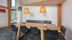 A dining area with a wooden table, black chairs, and hanging pendant lights. - Villa Near Sint Maartenszee Beach With Jacuzzi (Sint Maartensvlotbrug)