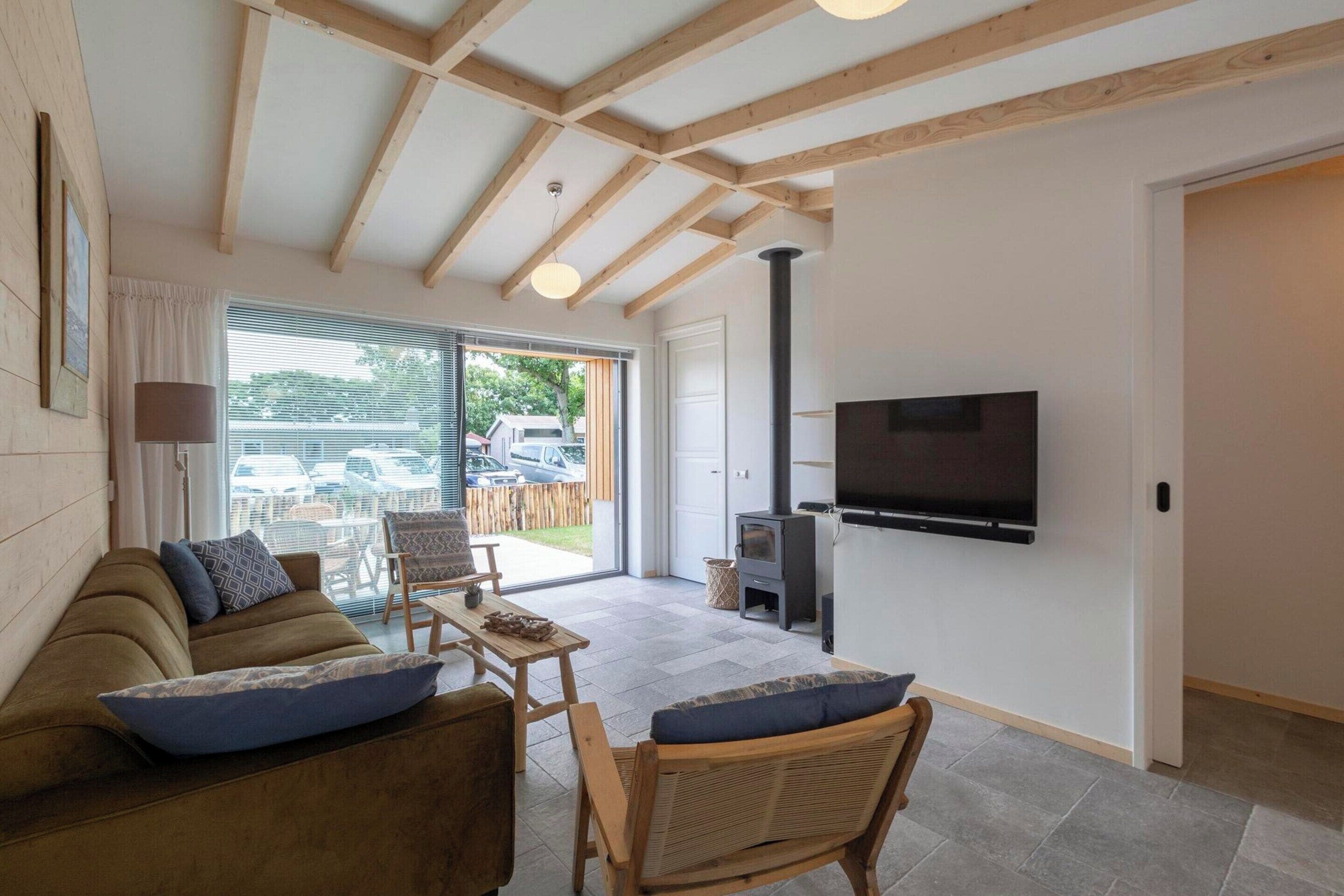 A modern living room with a sofa, chairs, a TV, and a fireplace.