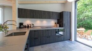 Una cocina moderna con armarios oscuros, un lavamanos de acero inoxidable y un horno empotrado.