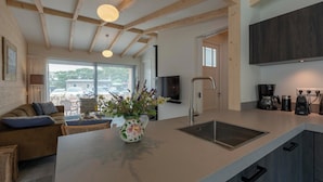 Una cocina moderna con una isla grande, vigas de madera, un televisor de pantalla plana y una estación de café.