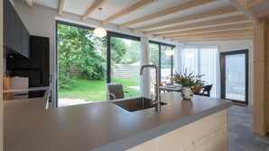 Una cocina moderna con una isla grande, vigas de madera y vistas al jardín.