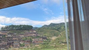 Un village traditionnel avec des maisons à étages et une structure en bois recouverte d’un toit, visible au premier plan.