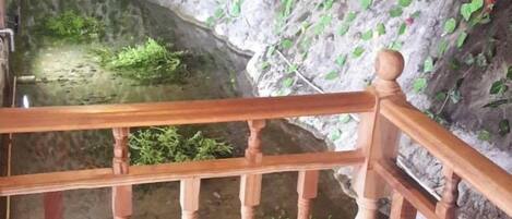 A wooden staircase leading to a cave-like area with a small pond.