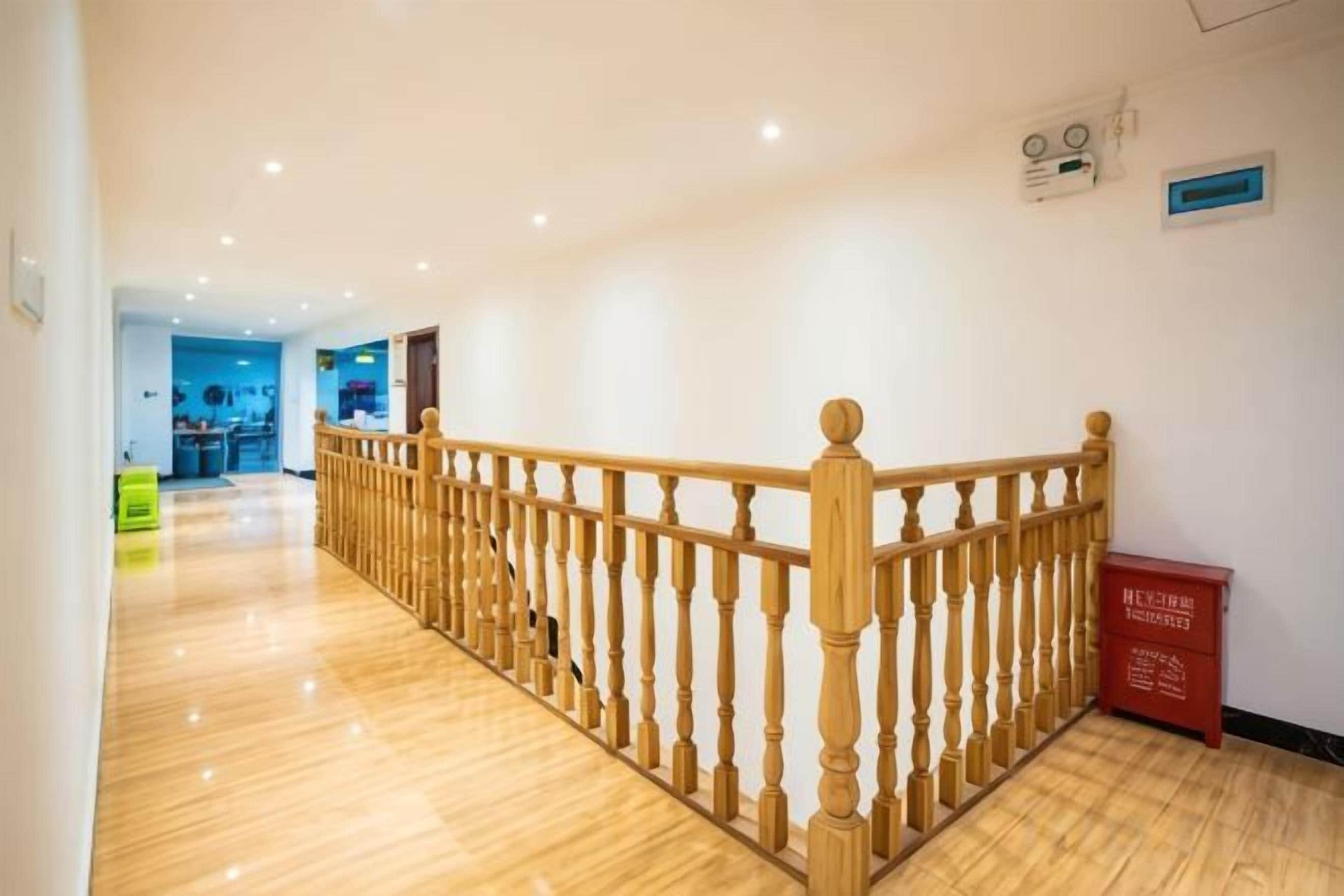 A hotel corridor with a wooden railing, a reception desk, and a red box on the floor.