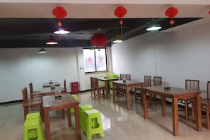 A dining area with tables and chairs, a window with a view, and red lanterns on the ceiling. - Xijiang miao village listen to tao xuan hotel (Leishan)