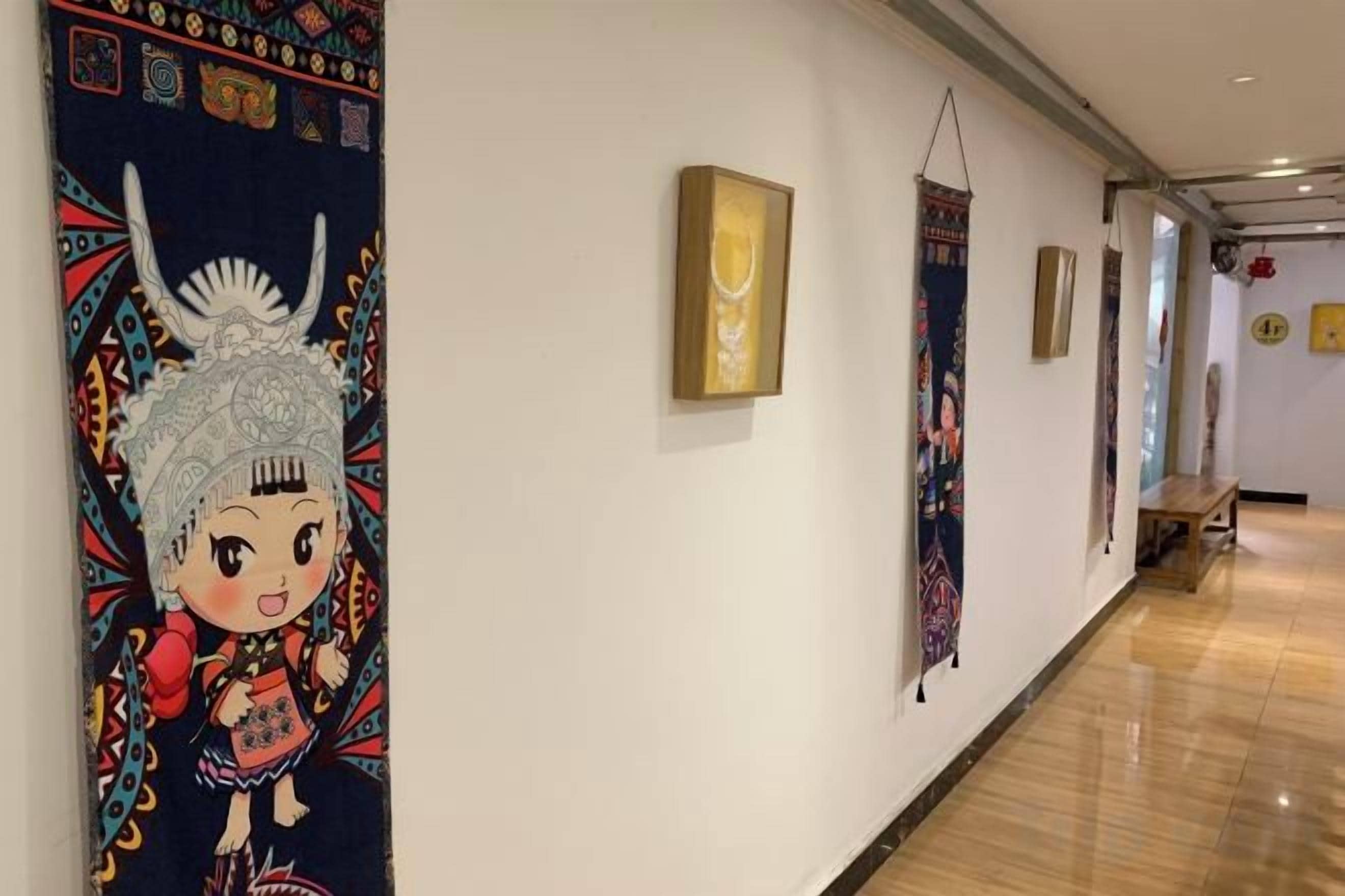 A hallway with artwork on the walls, a wooden bench, and a polished floor.