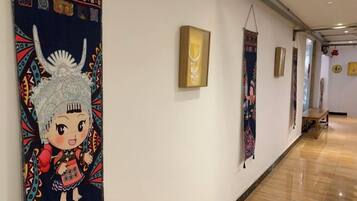 A hallway with artwork on the walls, a wooden bench, and a polished floor.