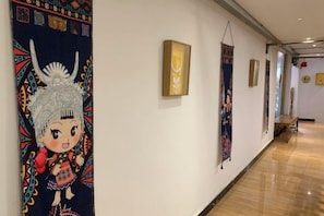 A hallway with artwork on the walls, a wooden bench, and a polished floor. - Xijiang miao village listen to tao xuan hotel (Leishan)