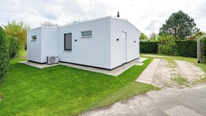A small, modern white building with a flat roof, a single door, and a small window. - Eureka 36 Bungalow for 4-guests With Garden (Sint Maartensvlotbrug)