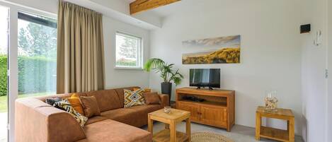 A modern living room with a brown sofa, wooden coffee table, and a TV stand.