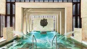 A spa area with a stone wall, a water feature, and a metal railing. - SLS Playa Mujeres – ALL Inclusive Collection (Punta Sam)