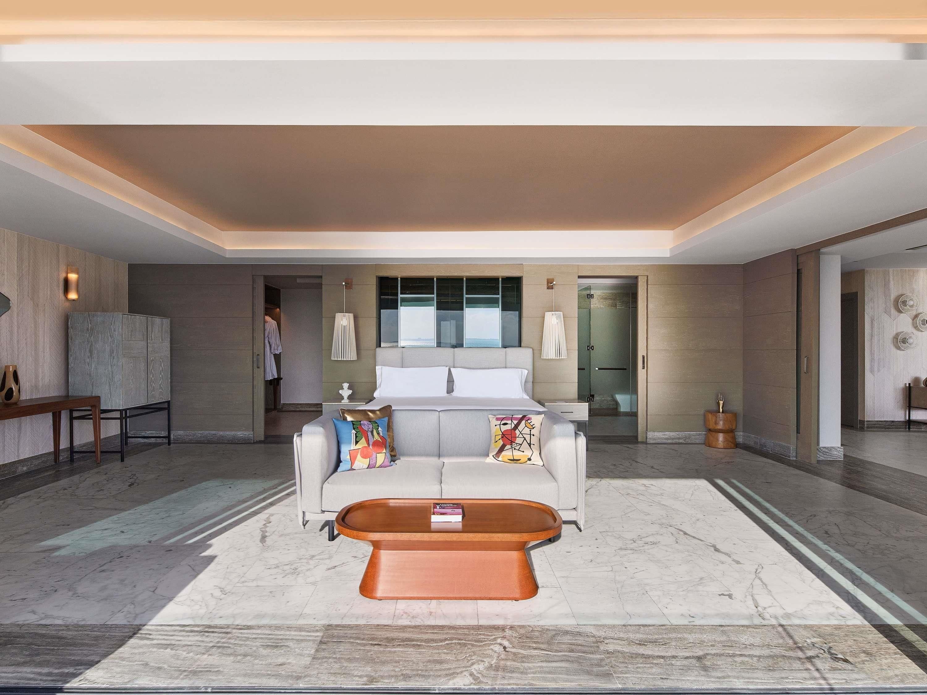 A modern hotel lobby with a sofa, coffee table, and a large mirror.