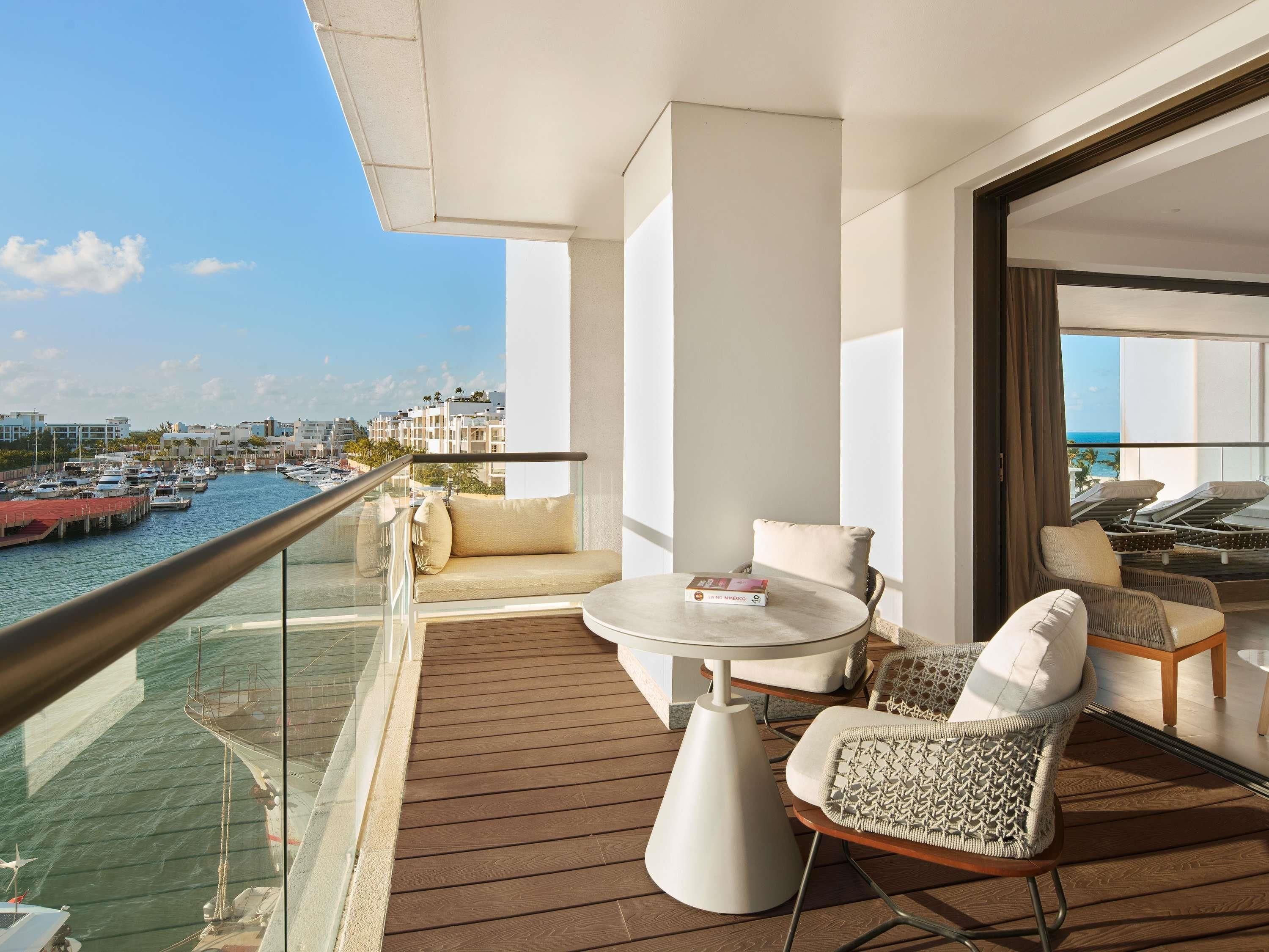 A balcony with a wooden floor, a round table, and two wicker chairs.