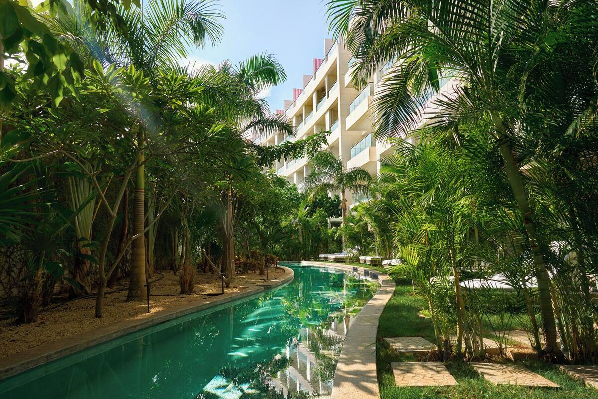 Una piscina rodeada de exuberante vegetación y un edificio de varios pisos.