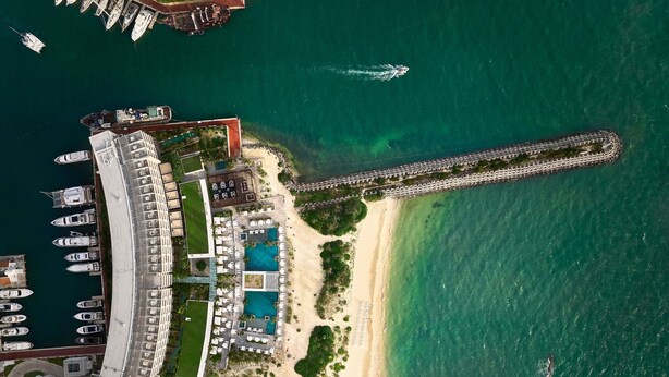 An aerial view of a coastal resort with a marina, swimming pools, and a long pier. - SLS Playa Mujeres – ALL Inclusive Collection (Punta Sam)