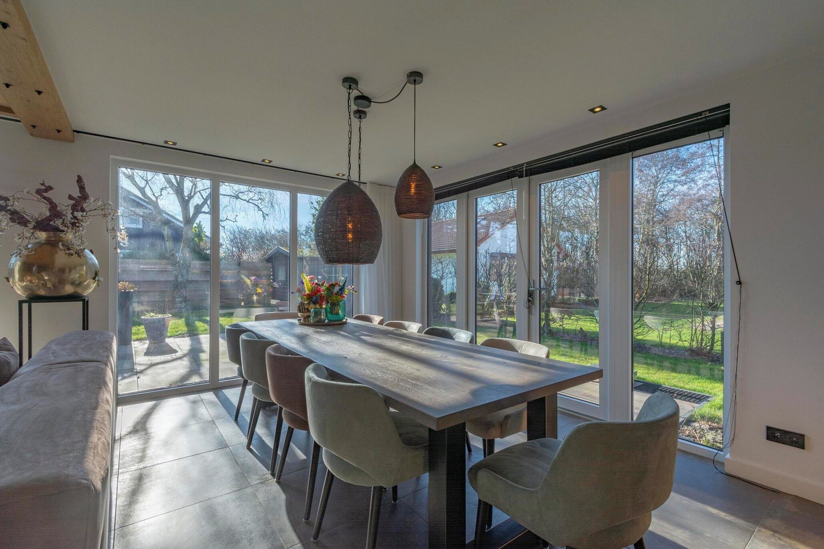 Een eethoek met een grote tafel, stoelen en hanglampen.