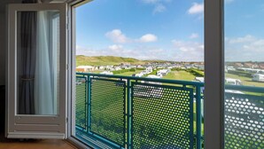 Un balcon donnant sur un terrain de camping et des collines verdoyantes.