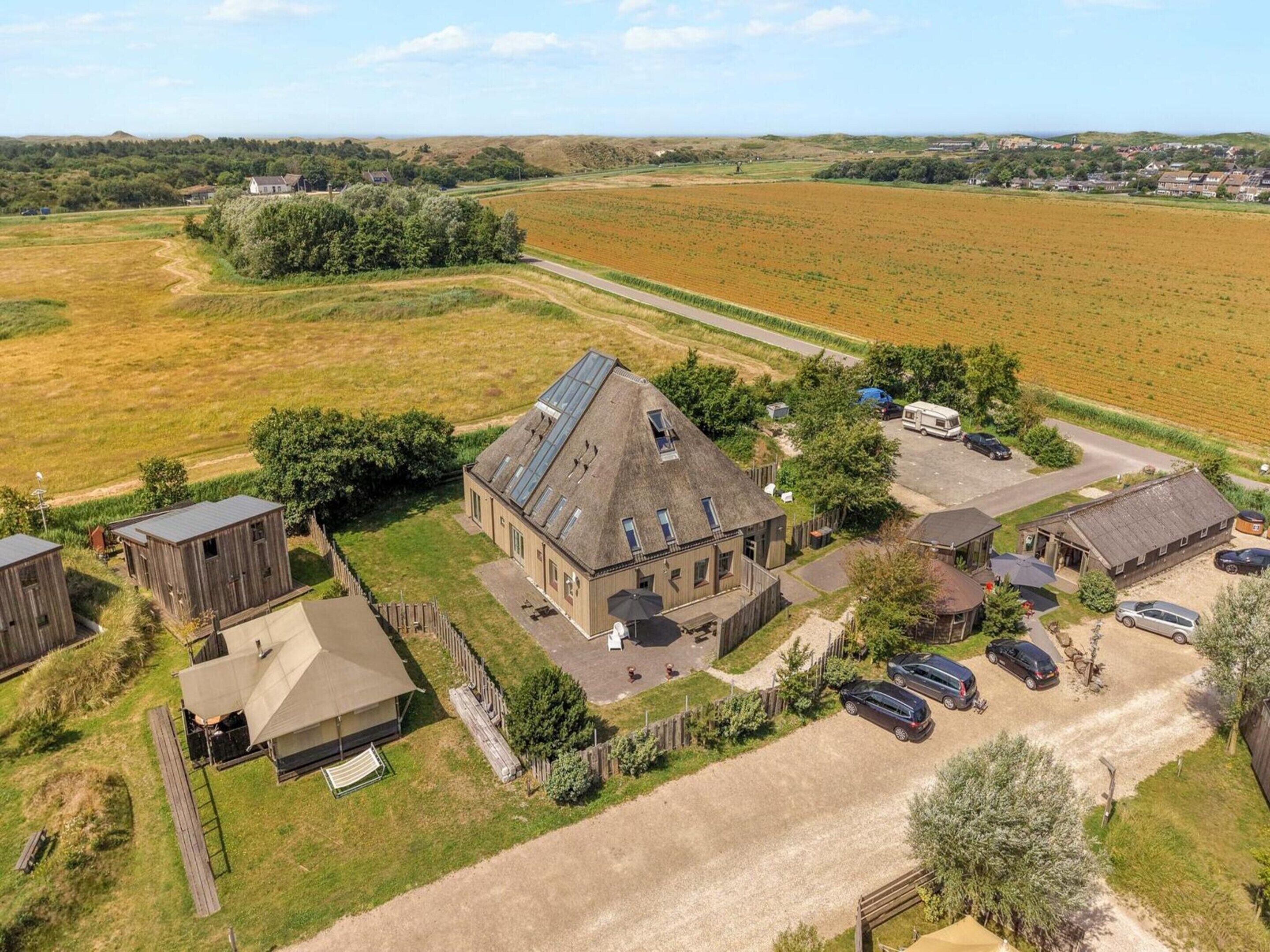 A rural property with a large barn, several smaller buildings, and a parking area with cars.