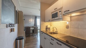 A modern kitchen with a microwave, sink, and stainless steel trash can. - Strandslag 193 Charming Apartment for 4-person (Julianadorp)