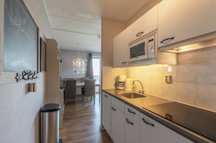Una cocina moderna con microondas, pileta y basurero de acero inoxidable.