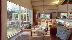 A spacious living area with large windows, a dining area, and a kitchen. - Sandepark 93 Home Near Groote Keeten Beach (Callantsoog)