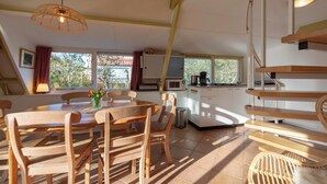 A modern kitchen with a microwave, coffee maker, and wooden cabinets. There is a dining area with a wooden table and chairs, and a staircase leading to an upper level. - Sandepark 93 Home Near Groote Keeten Beach (Callantsoog)