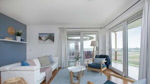 A modern living room with a white sofa, a blue armchair, and a small round table. - Residence Juliana 40 With Dune Views (Julianadorp)
