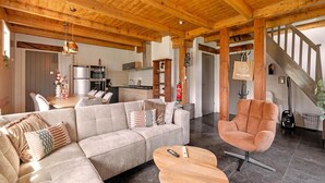 A spacious living area with a wooden ceiling, a sofa, a coffee table, and a staircase leading to another level. - Apartment With Garden in Dutch Countryside (Callantsoog)