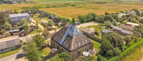 An aerial view of a rural property with multiple buildings, including a large house with a sloped roof and a smaller structure with a flat roof.