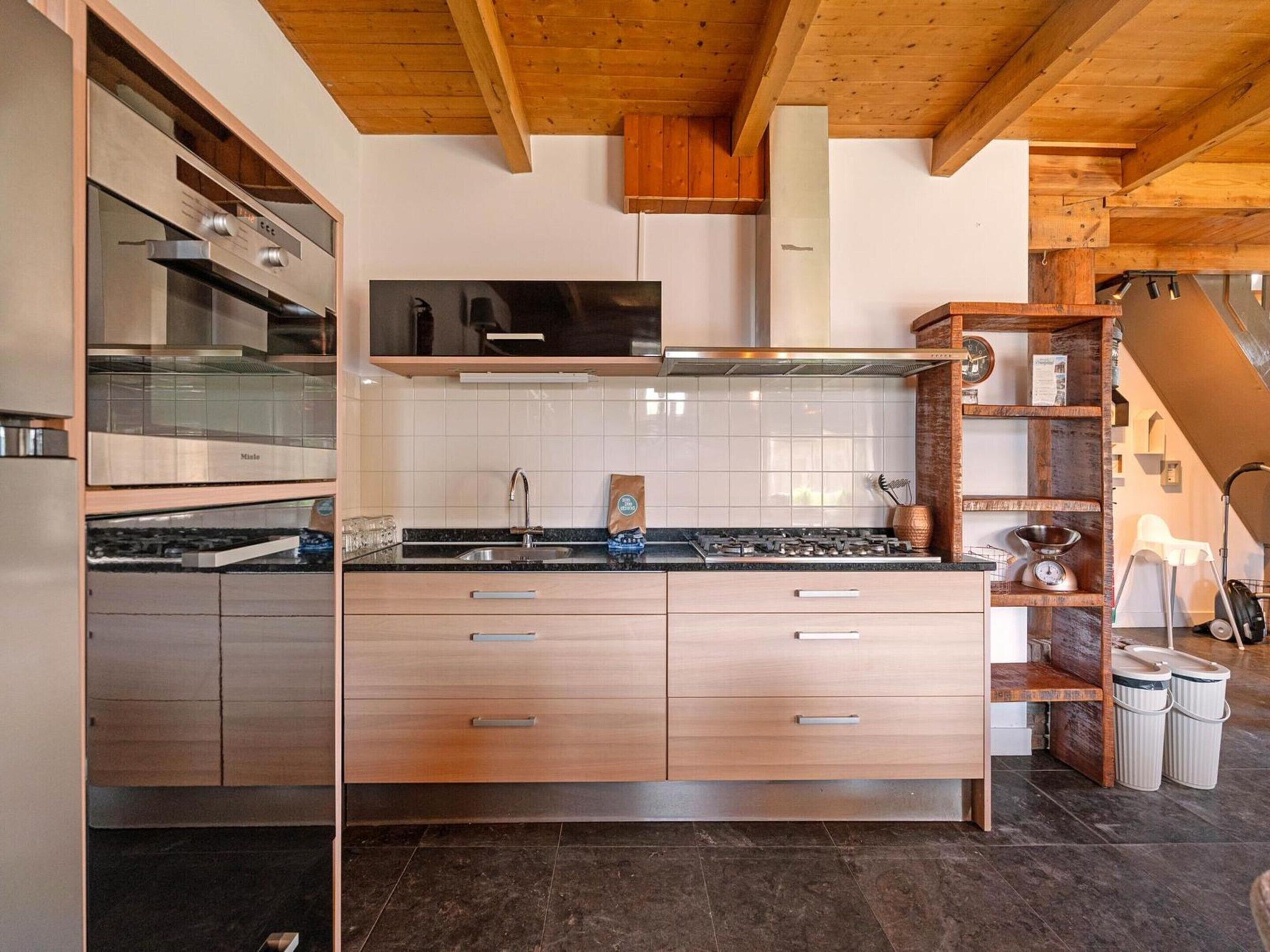 A modern kitchen with wooden cabinets, a stainless steel range hood, and a tiled backsplash.