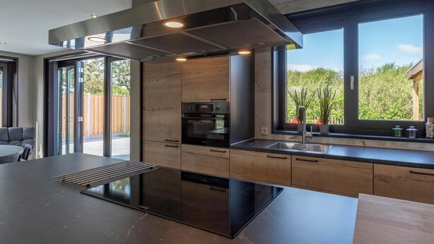A modern kitchen with a large island, built-in oven, and stainless steel range hood. - Villa Near North Holland Beach With Jacuzzi (Julianadorp)