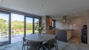 A modern kitchen with large windows, a dining area with chairs, and a view of the outdoors. - Villa Near North Holland Beach With Jacuzzi (Julianadorp)