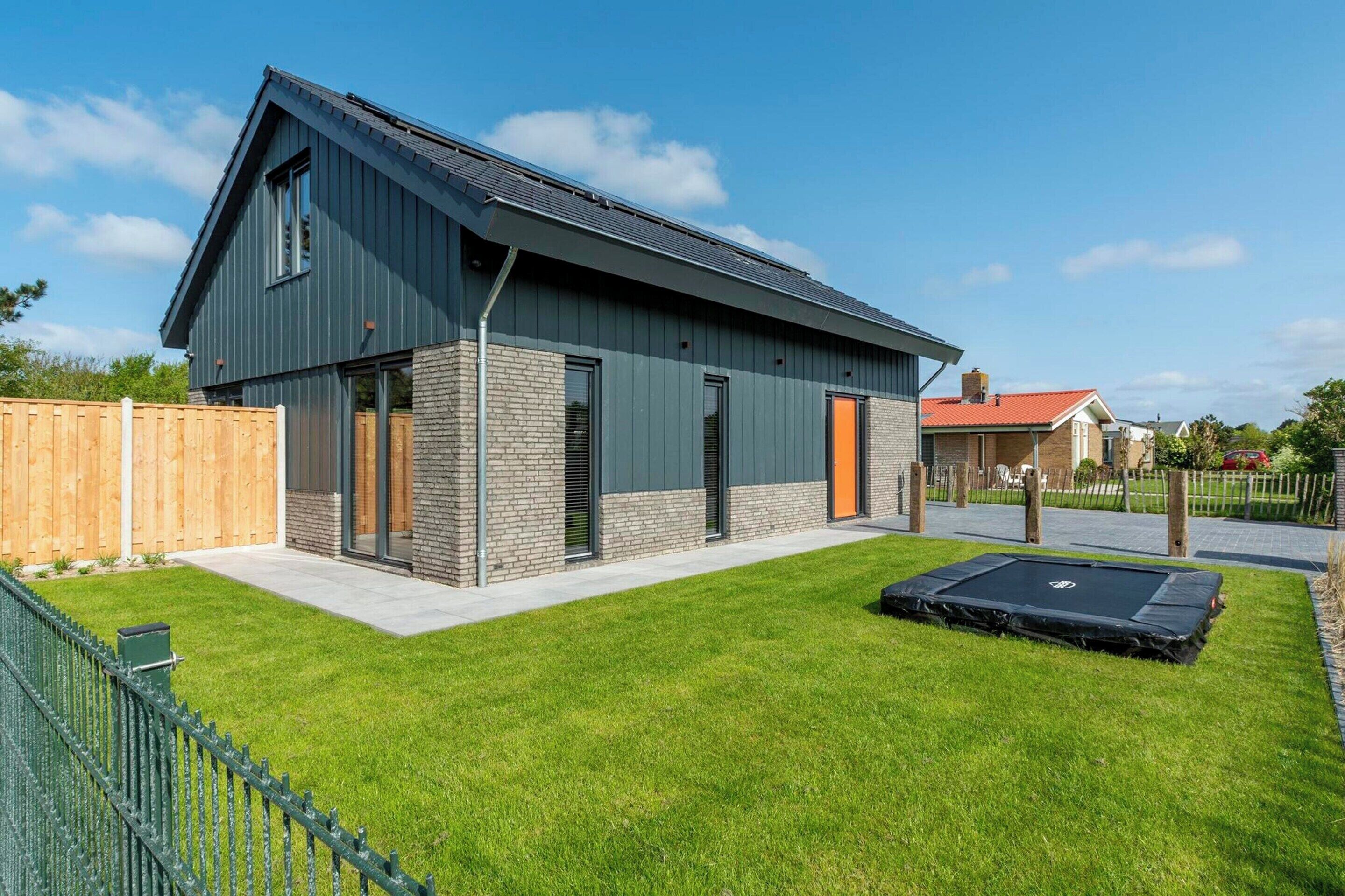 A modern two-story house with a sloped roof, a brick foundation, and a well-maintained lawn.