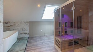 A modern bathroom with a skylight, a bathtub, and a glass-enclosed shower area. - Villa Near North Holland Beach With Jacuzzi (Julianadorp)