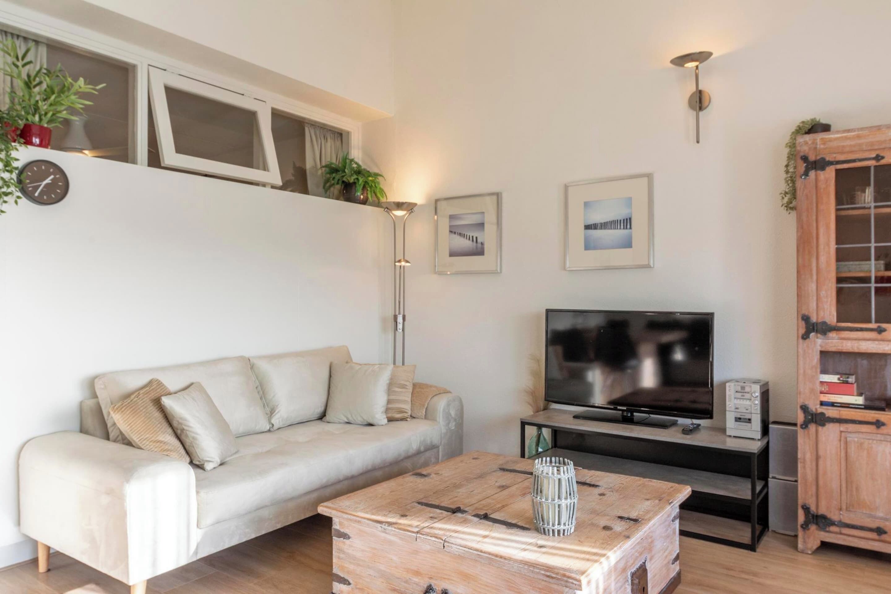 Un salon moderne avec un canapé, une table basse en bois, un téléviseur et un meuble.