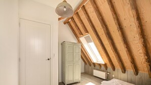 A bedroom with a sloped ceiling, a wardrobe, a radiator, and a door. - Vossehoeck 3 Apartment With Nature Reserve View (Callantsoog)