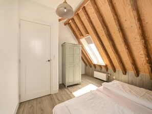 A bedroom with a sloped ceiling, a wardrobe, a radiator, and a door. - Vossehoeck 3 Apartment With Nature Reserve View (Callantsoog)