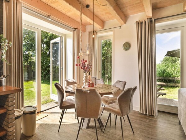 A dining area with a wooden table, chairs, and a vase of flowers. - Vossehoeck 3 Apartment With Nature Reserve View (Callantsoog)