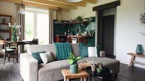 A cozy living room with a sofa, a coffee table, and a dining area with chairs. - Vossehoeck 4 Apartment in Callantsoog (Callantsoog)