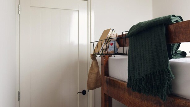 A bunk bed with a green towel, a white pillow, and a small shelf with books and a teddy bear. - Vossehoeck 4 Apartment in Callantsoog (Callantsoog)
